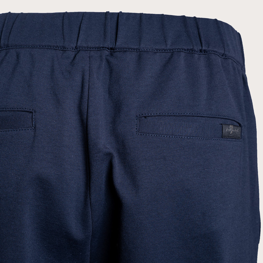 Close-up of the back waistband and pockets of navy blue trousers, showing a small dark brand label on the right pocket. 7 For All Mankind Trousers available at Sakks Menswear in Southampton.