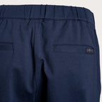 Close-up of the back waistband and pockets of navy blue trousers, showing a small dark brand label on the right pocket. 7 For All Mankind Trousers available at Sakks Menswear in Southampton.
