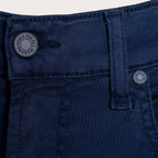 A detailed close up of a pair of jeans in a deep navy Colour. The image shows the belt loop and waistband of a pair of 7 For All Mankind Slimmy Sateen Jeans. The button reads "Seven For All Mankind". Sakks Menswear Southampton
