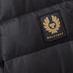 Close-up of a black puffer jacket showing the Belstaff logo patch on the chest. Belstaff Down Jacket. Sakks Menswear Southampton.