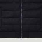 Close-up of a black quilted puffer jacket showing horizontal stitching, a central zipper, and ribbed knit trim at the bottom. Belstaff Gilet. Sakks Menswear Southampton.