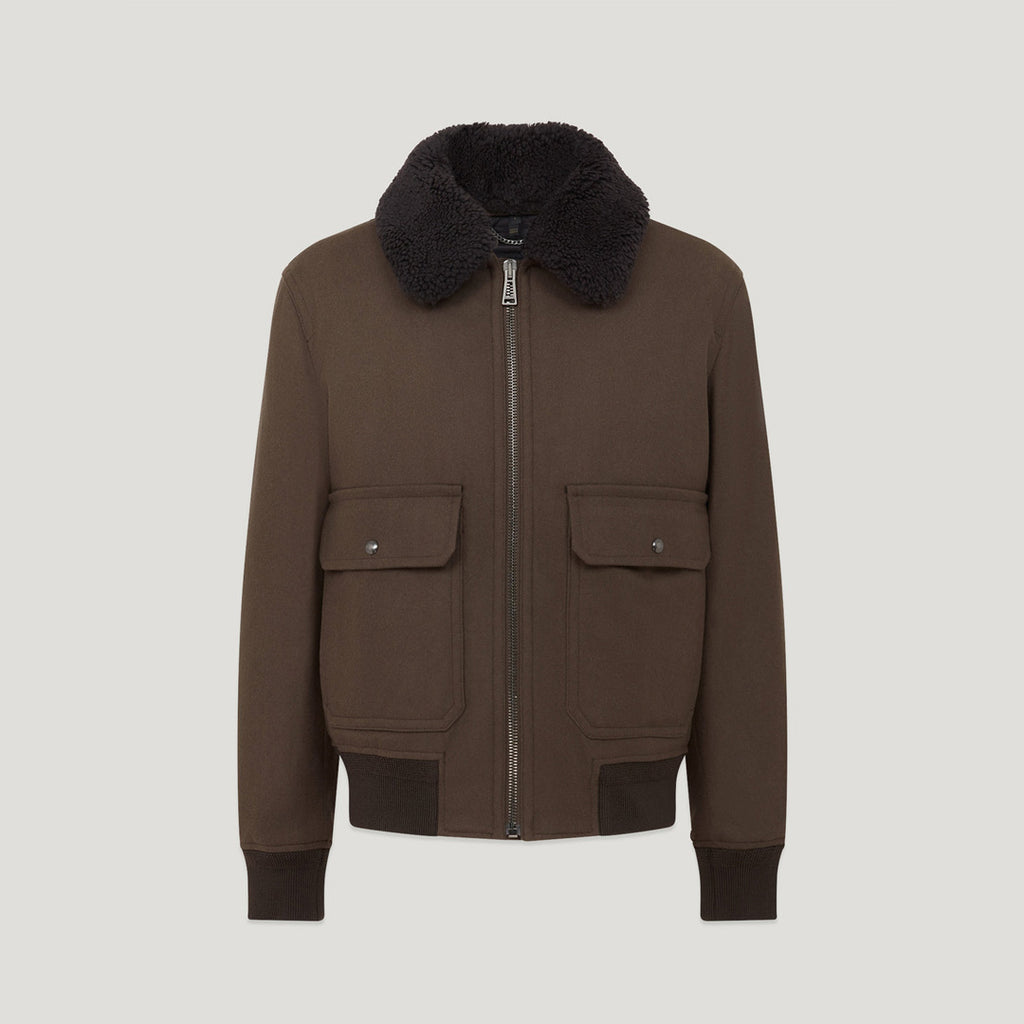 A dark brown jacket with a black faux-fur collar, front zipper, and two flap pockets, shown on a light gray background. Belstaff Welder Jacket. Sakks Menswear Southampton.