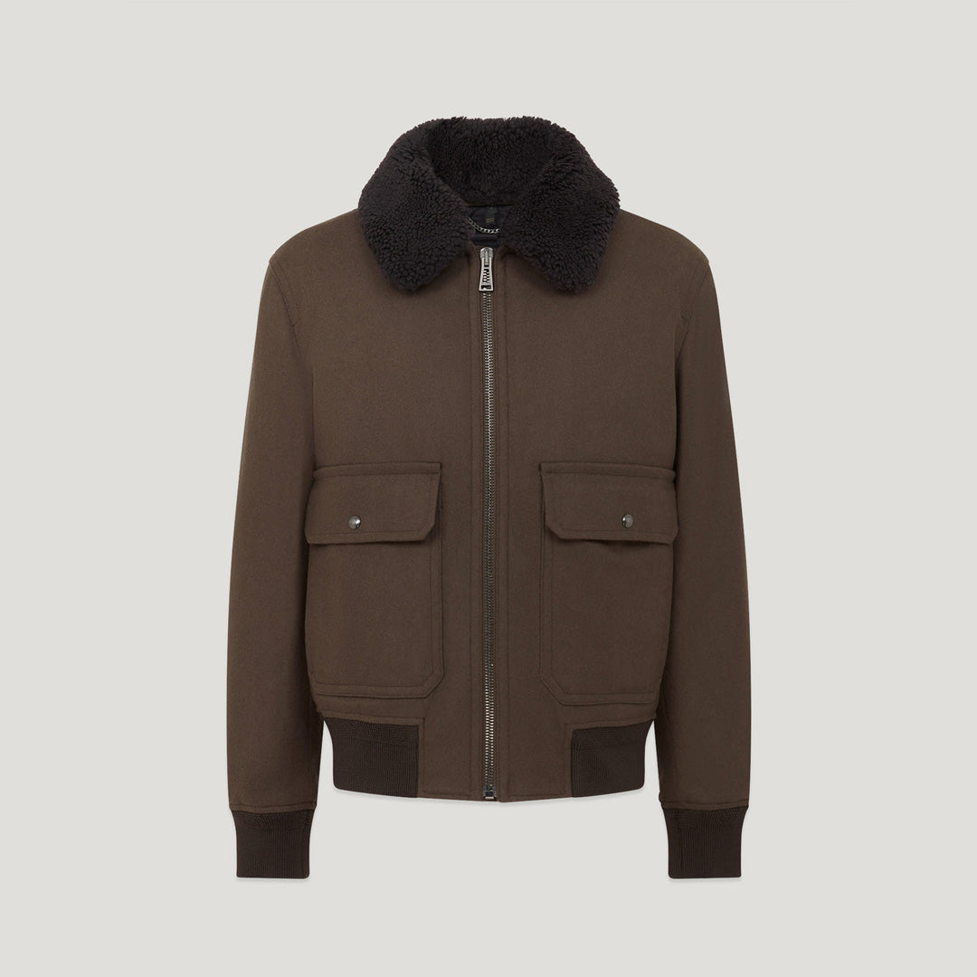 A dark brown jacket with a black faux-fur collar, front zipper, and two flap pockets, shown on a light gray background. Belstaff Welder Jacket. Sakks Menswear Southampton.