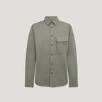 A long-sleeve button-up shirt in a muted sage green color, featuring a single chest pocket and dark buttons, displayed against a solid light gray background. Belstaff Shirt. Sakks Menswear Southampton.