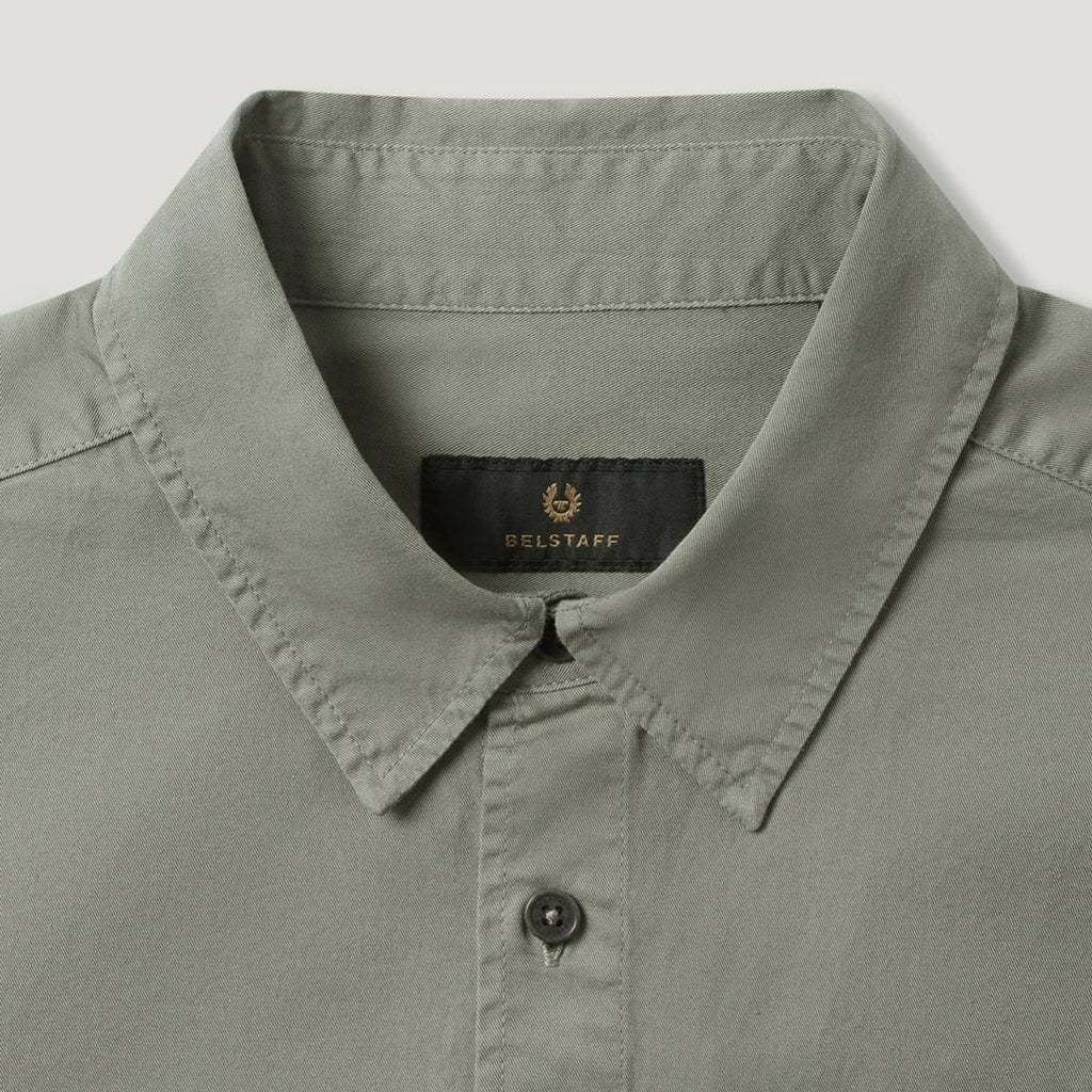 Close-up of a light sage green collared shirt by Belstaff, showing the inner neck label with the brand name and logo. Belstaff Shirt. Sakks Menswear Southampton.