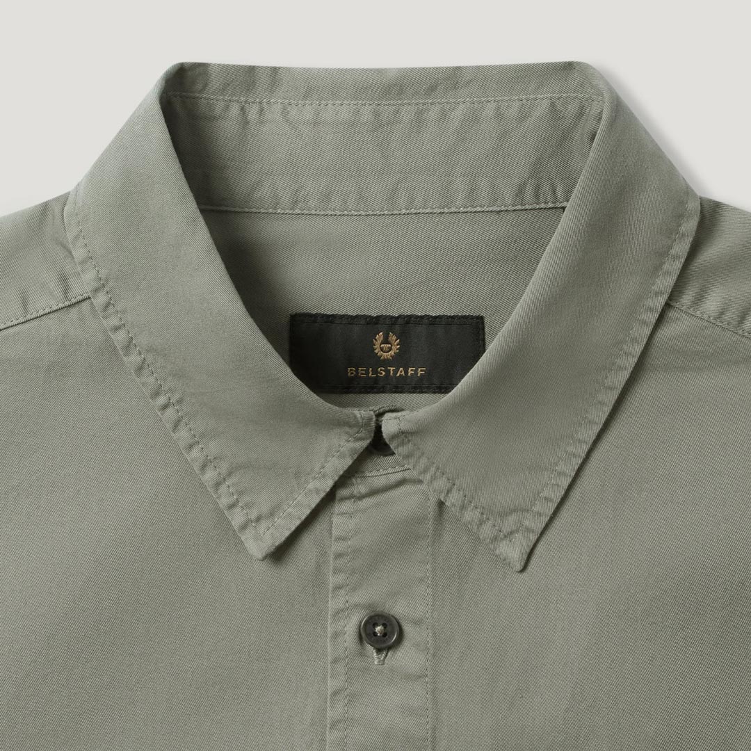 Close-up of a light sage green collared shirt by Belstaff, showing the inner neck label with the brand name and logo. Belstaff Shirt. Sakks Menswear Southampton.