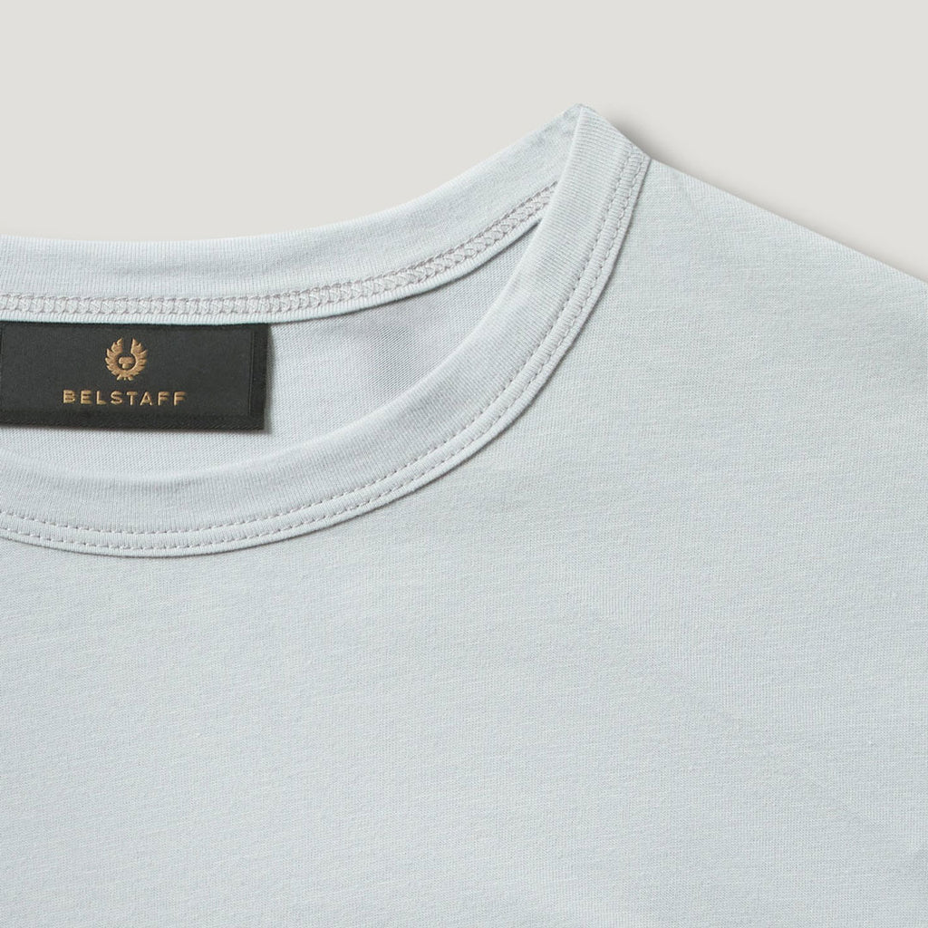 Close-up of a light blue crew-neck t-shirt showing the inner neck label with the gold Belstaff logo and brand name. Belstaff T-Shirt. Sakks Menswear Southampton.