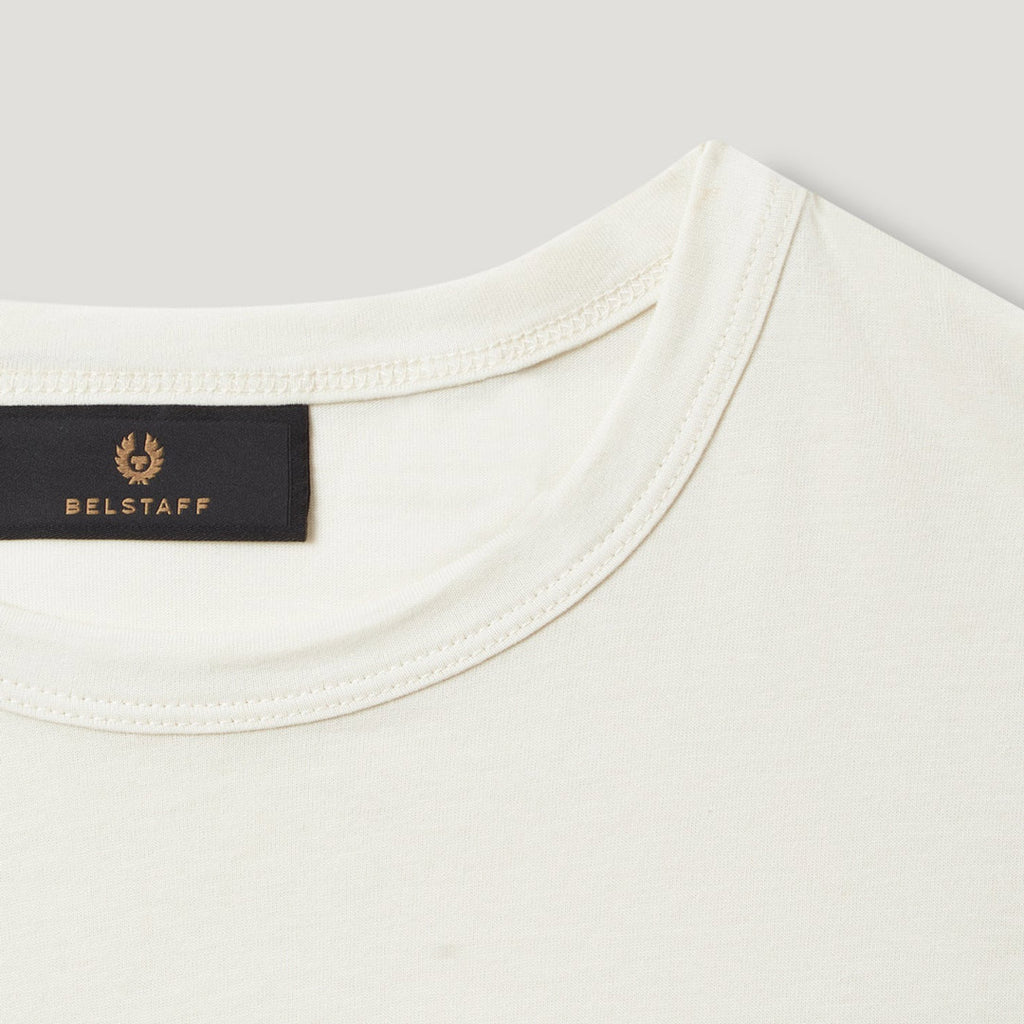 Close-up of a cream-colored crewneck t-shirt showing the inner collar with a black BELSTAFF brand label. Belstaff T-Shirt. Sakks Menswear Southampton.