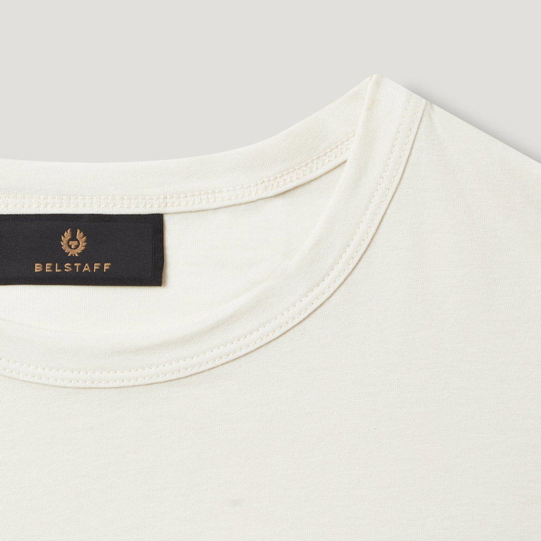 Close-up of a cream-colored crewneck t-shirt showing the inner collar with a black BELSTAFF brand label. Belstaff T-Shirt. Sakks Menswear Southampton.