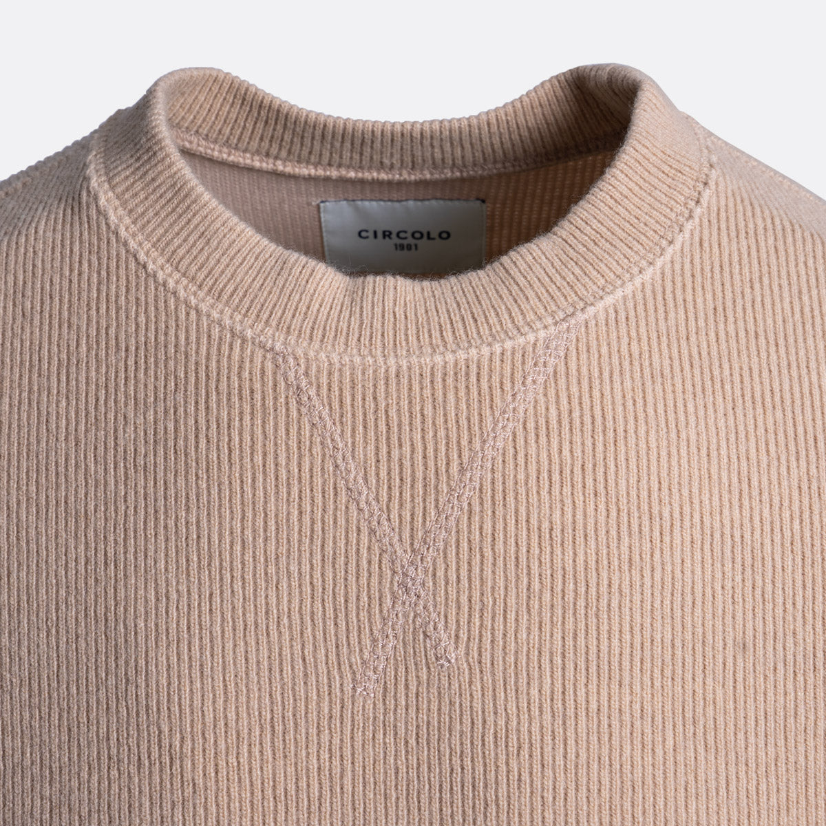 Close-up of a ribbed knit crewneck sweater in a soft dusty pink color, showing the inner neck label with the brand name 'CIRCOLO 1901'. Circolo 1901 Jumper available at Sakks Menswear in Southampton.