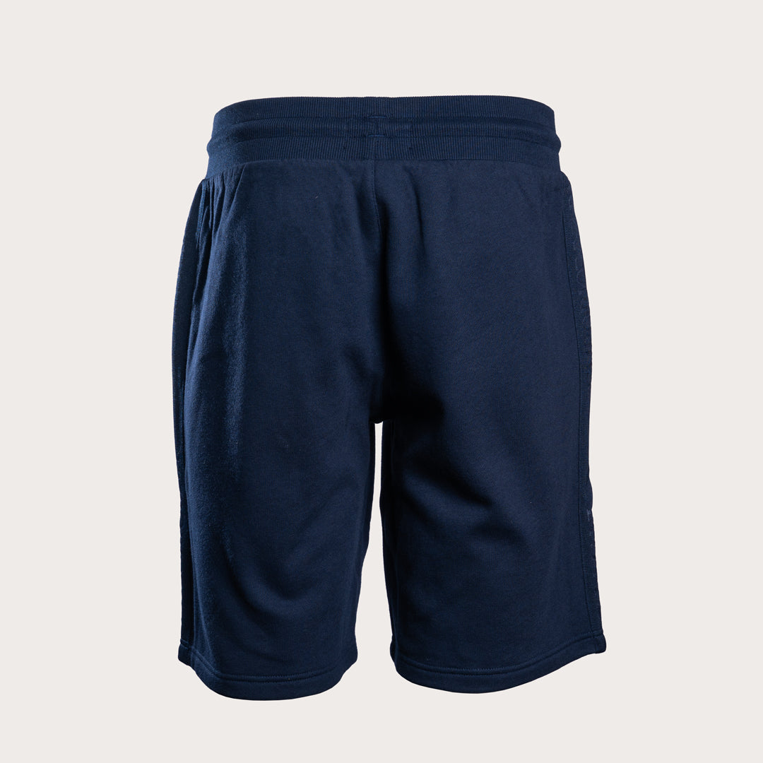 A pair of dark navy blue athletic shorts with an elastic waistband, shown from the back on a light beige background. Emporio Armani Shorts. Sakks Menswear Southampton.