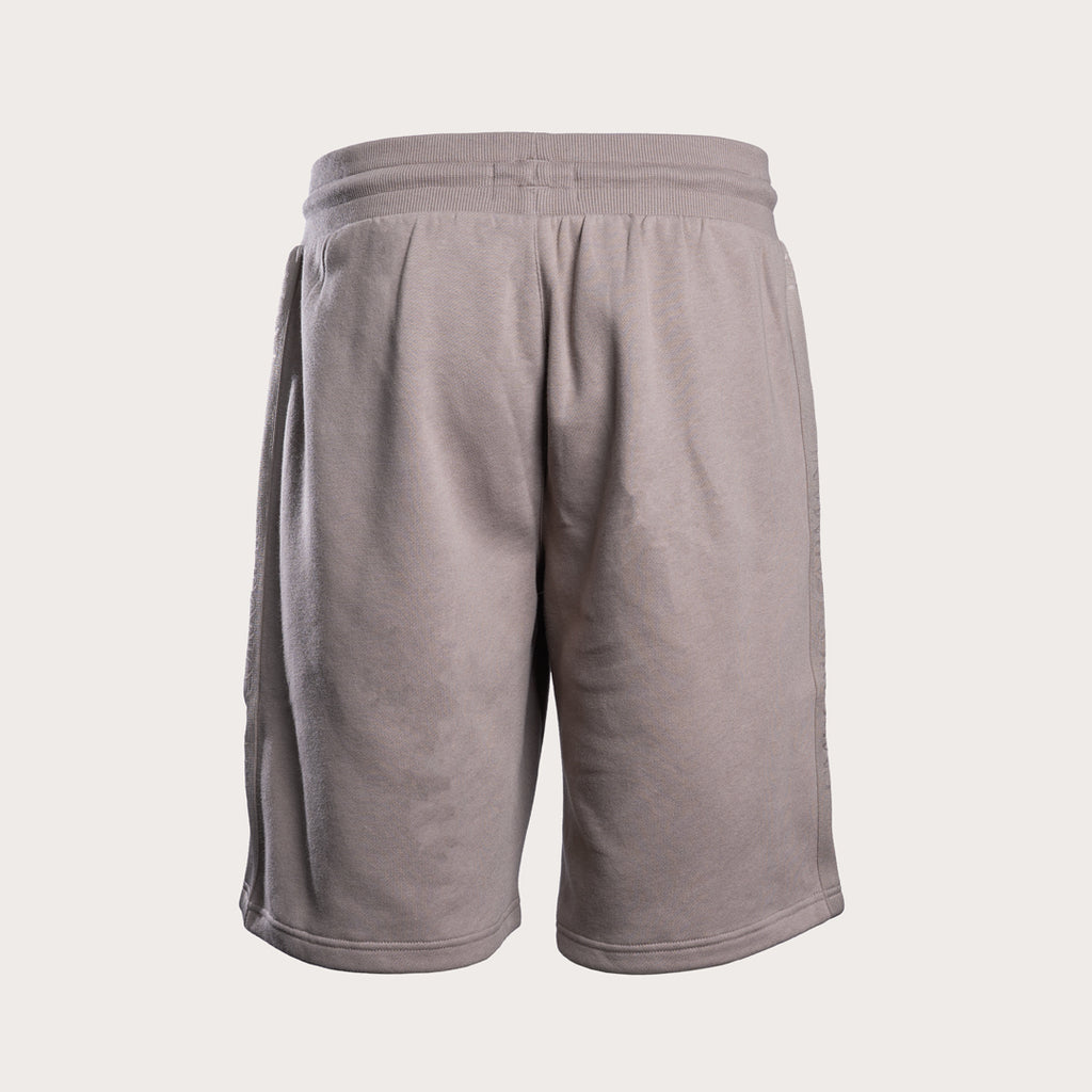 A pair of light taupe gray athletic shorts with a ribbed elastic waistband, shown from the back on a light beige background. Emporio Armani Sweat Shorts. Sakks Menswear Southampton.