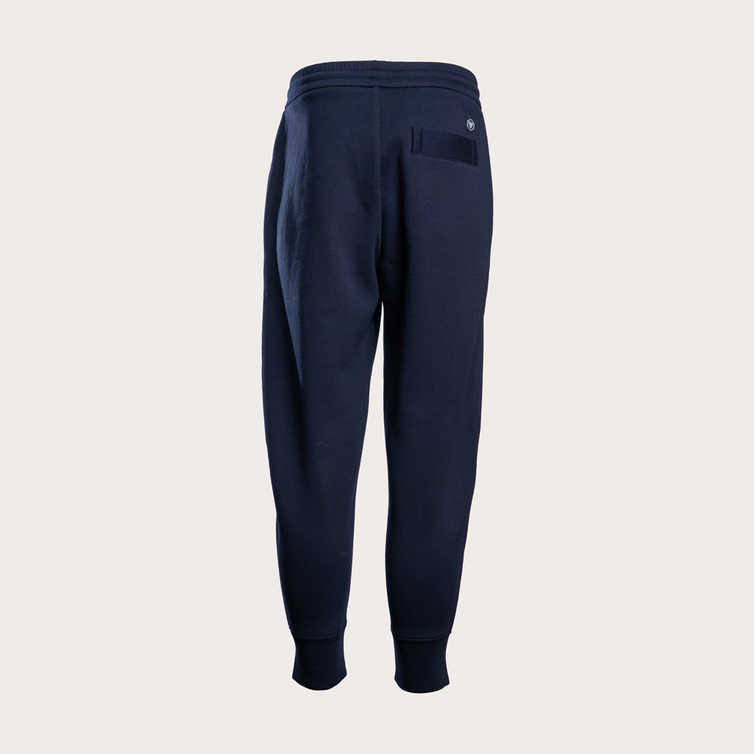 A pair of navy blue sweatpants shown from the back, featuring a relaxed fit, elastic waistband, and a small circular logo on the upper right side, set against a solid light gray background. Emporio Armani Sweat Pants. Sakks Menswear Southampton.