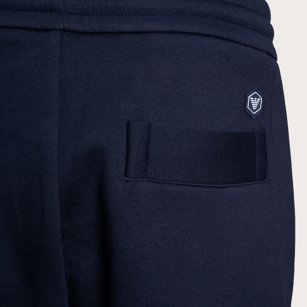 Close-up of navy blue sweatpants showing the back pocket with a hook-and-loop closure and a small embroidered shield logo on the upper back. Emporio Armani Sweat Pants. Sakks Menswear Southampton.