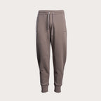 A pair of men's jogger sweatpants in a muted taupe-brown color, featuring an elastic waistband with a white drawstring, side pockets, and ribbed ankle cuffs, shown against a solid light gray background. Emporio Armani Sweat Pants. Sakks Menswear Southampton.