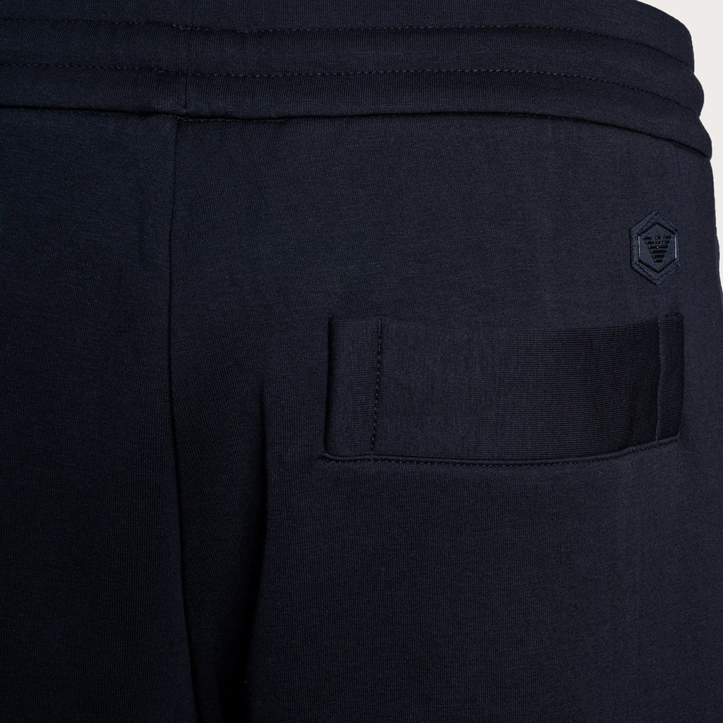 Close-up of dark navy athletic sweatpants showing a side pocket with a tonal embroidered logo on the upper right side. Emporio Armani Sweat Pants. Sakks Menswear Southampton.