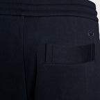 Close-up of dark navy athletic sweatpants showing a side pocket with a tonal embroidered logo on the upper right side. Emporio Armani Sweat Pants. Sakks Menswear Southampton.