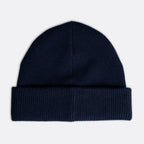 A dark navy blue knit beanie hat with a folded cuff, shown flat against a light gray background. Emporio Armani Beanie. Sakks Menswear Southampton.