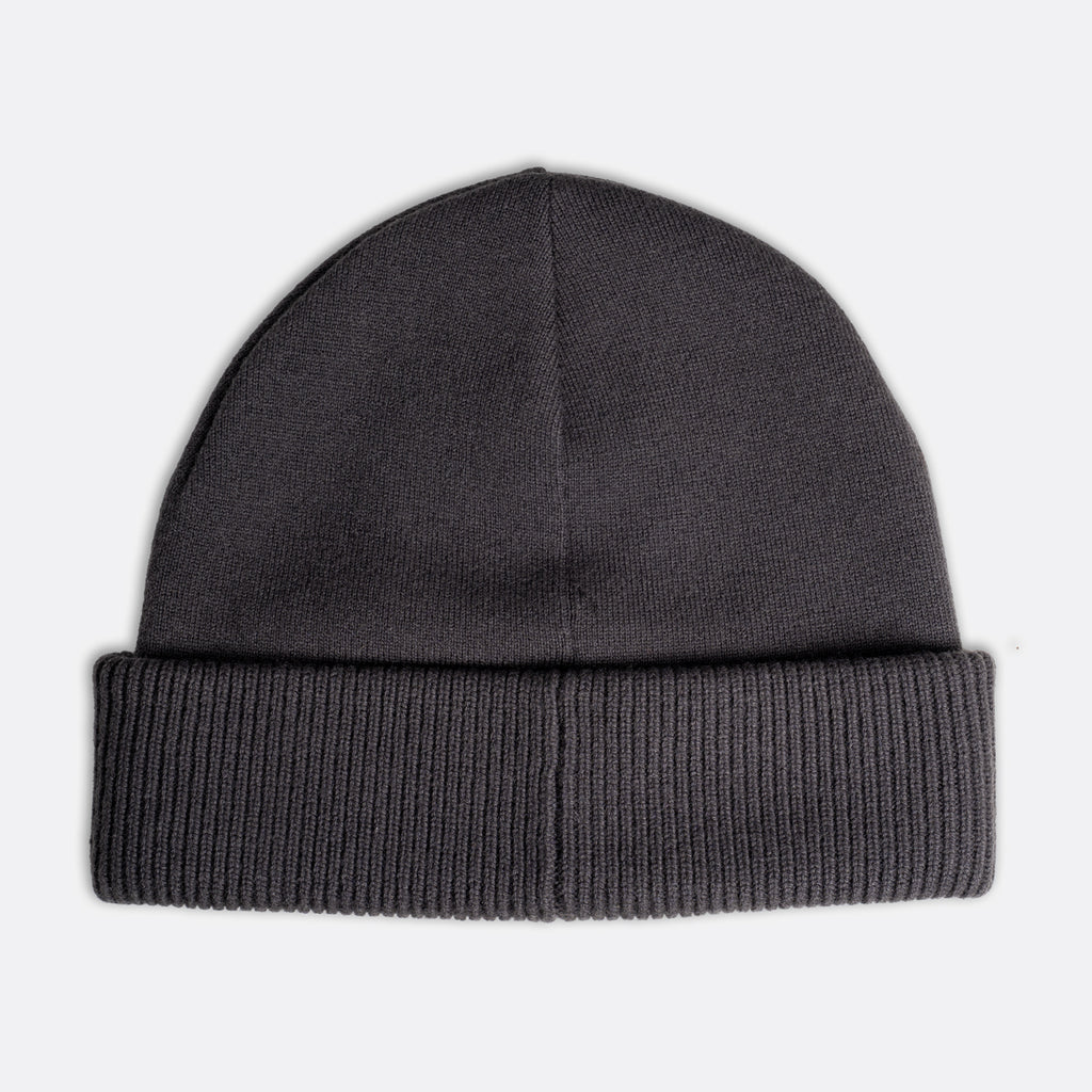 A dark gray ribbed knit beanie hat shown flat against a light gray background. Emporio Armani Beanie. Sakks Menswear Southampton.