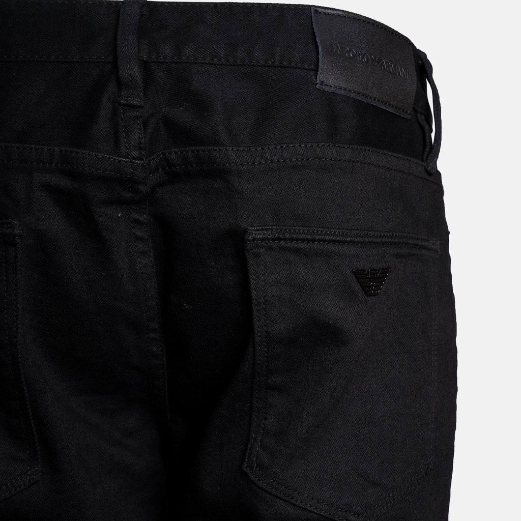 Close-up of the back waistband and right rear pocket of black Emporio Armani jeans, showing the brand patch and logo. Emporio Armani Jeans. Sakks Menswear Southampton.
