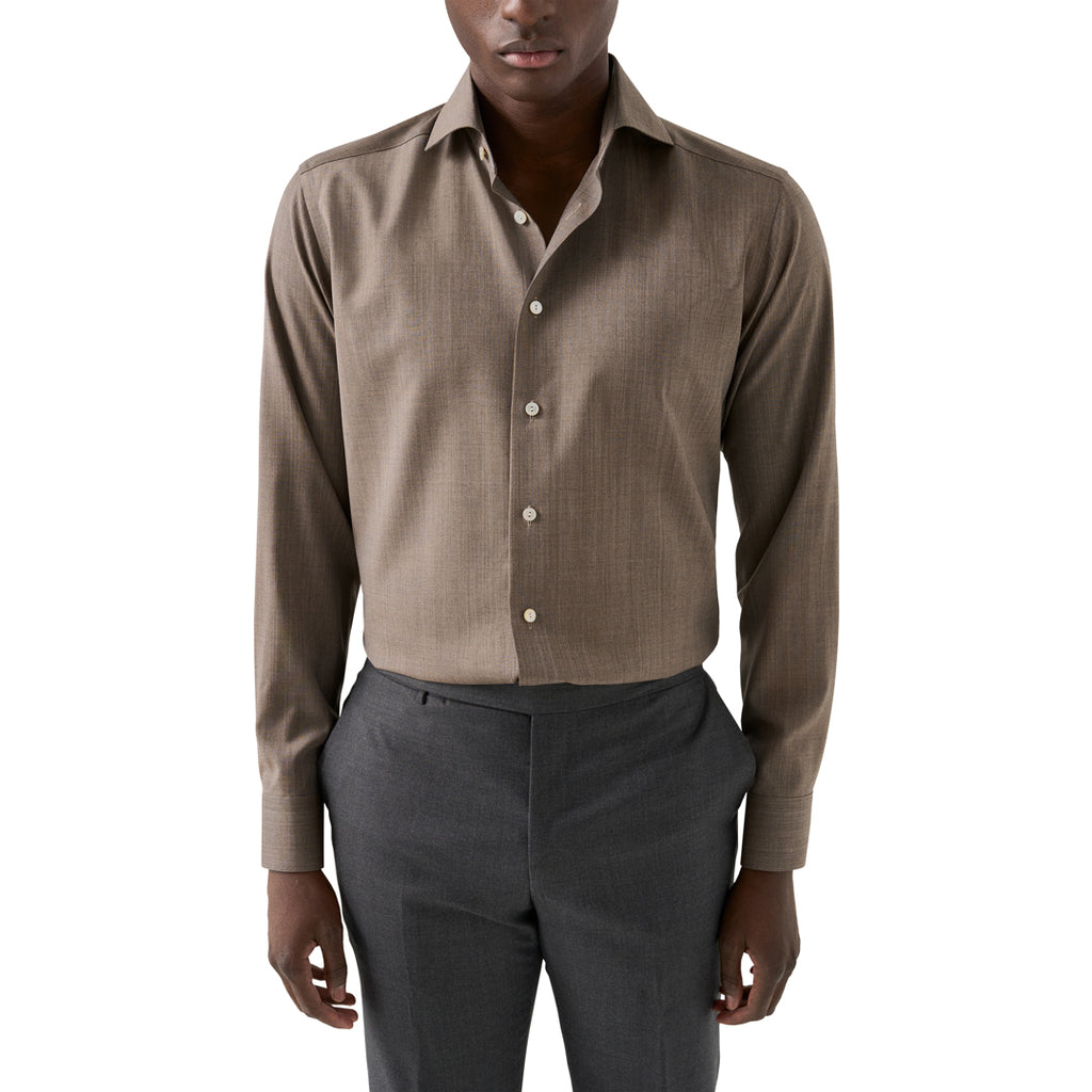 A man wearing a brown long-sleeve button-down shirt and dark grey trousers, cropped from the mouth down against a plain white background. Eton Shirt available at Sakks Menswear in Southampton.