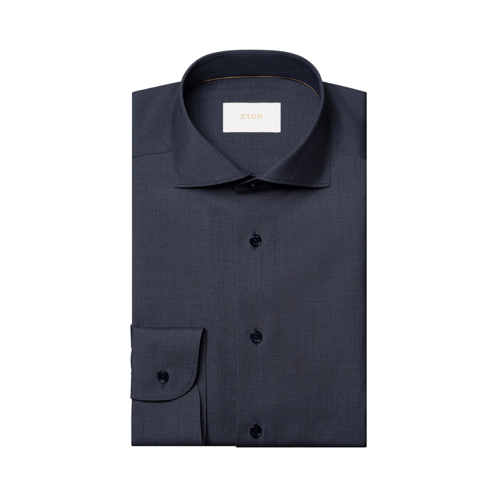 A folded dark navy blue dress shirt with a spread collar and button front, shown on a plain white background. A small white neck label is visible inside the collar. Eton Shirt available at Sakks Menswear in Southampton.