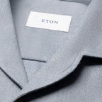 Close-up of a light gray textured fabric garment with a white neck label reading ETON. Eton Shirt available at Sakks Menswear in Southampton.