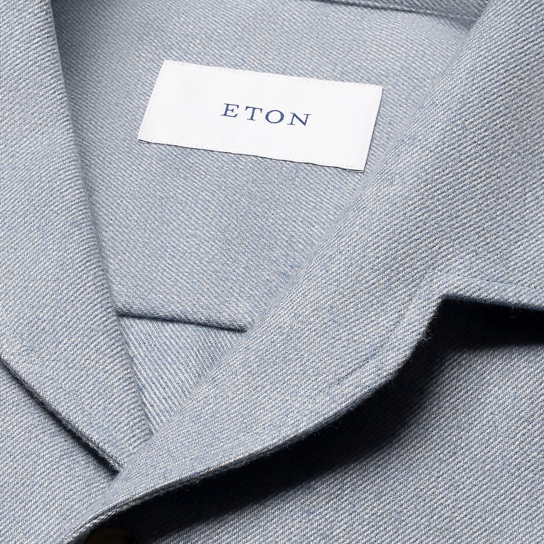 Close-up of a light gray textured fabric garment with a white neck label reading ETON. Eton Shirt available at Sakks Menswear in Southampton.