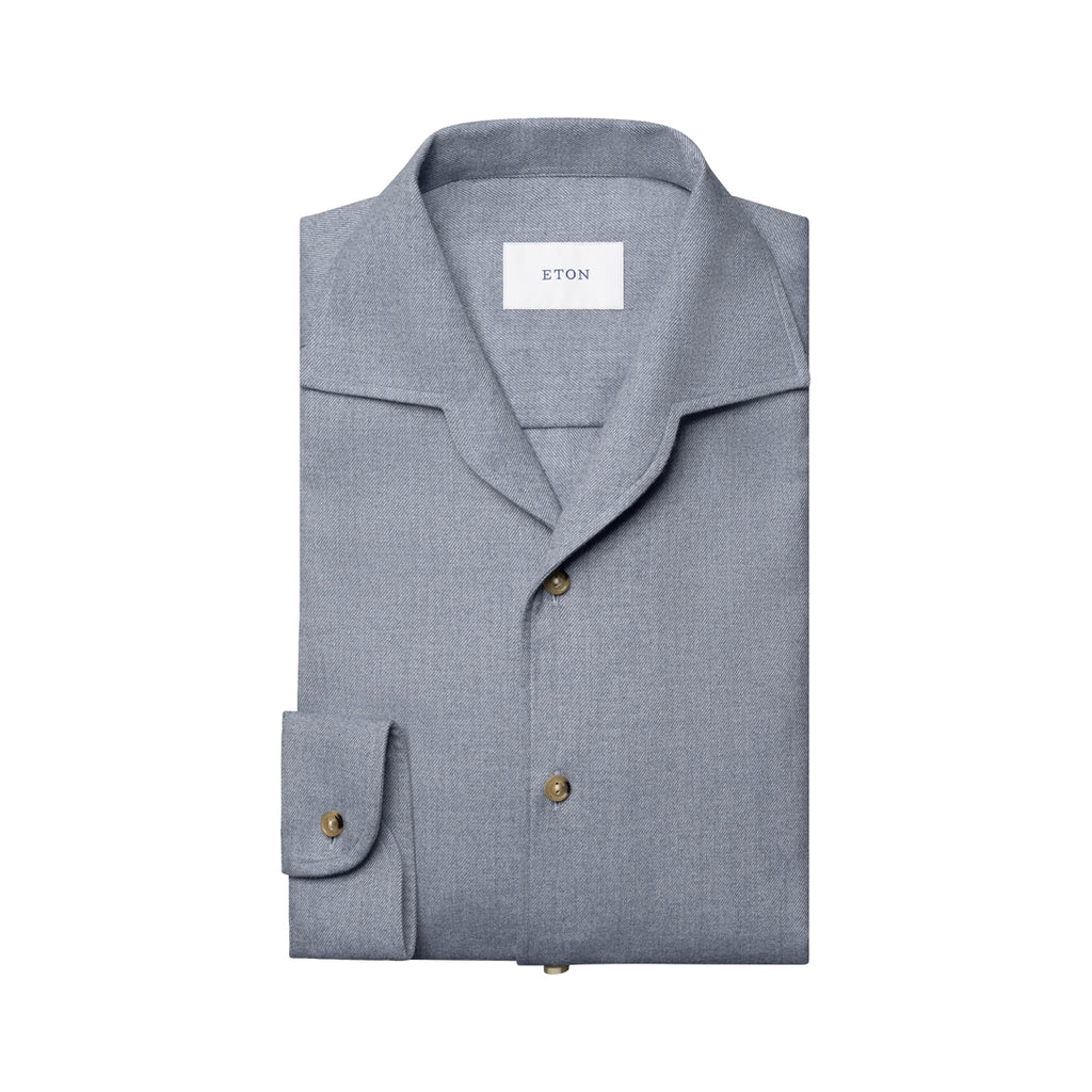 A folded light gray long-sleeve shirt with a spread collar and brass buttons, featuring a visible ETON brand label inside the collar, set against a plain white background. Eton Shirt available at Sakks Menswear in Southampton.
