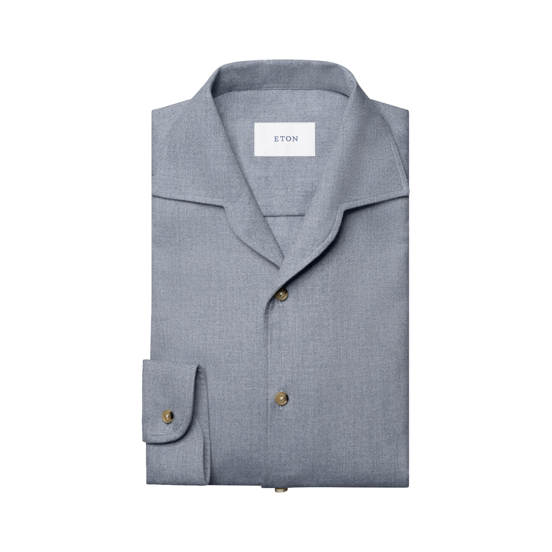A folded light gray long-sleeve shirt with a spread collar and brass buttons, featuring a visible ETON brand label inside the collar, set against a plain white background. Eton Shirt available at Sakks Menswear in Southampton.
