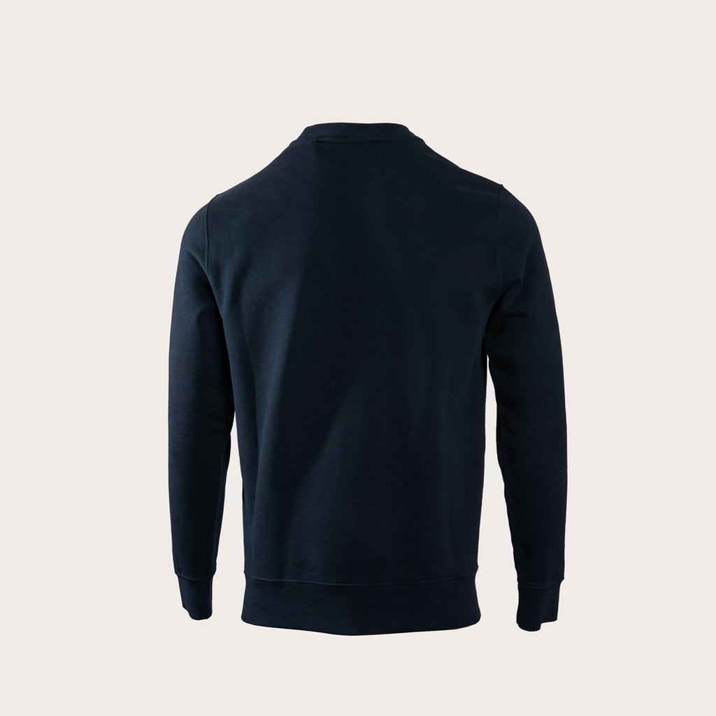 A dark navy blue long-sleeve crewneck sweatshirt shown from the back, photographed on a clean, solid light beige background. MA.Strum Sweatshirt available at Sakks Menswear in Southampton.