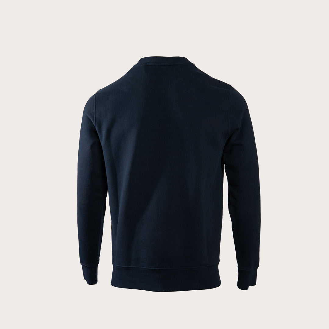 A dark navy blue long-sleeve crewneck sweatshirt shown from the back, photographed on a clean, solid light beige background. MA.Strum Sweatshirt available at Sakks Menswear in Southampton.