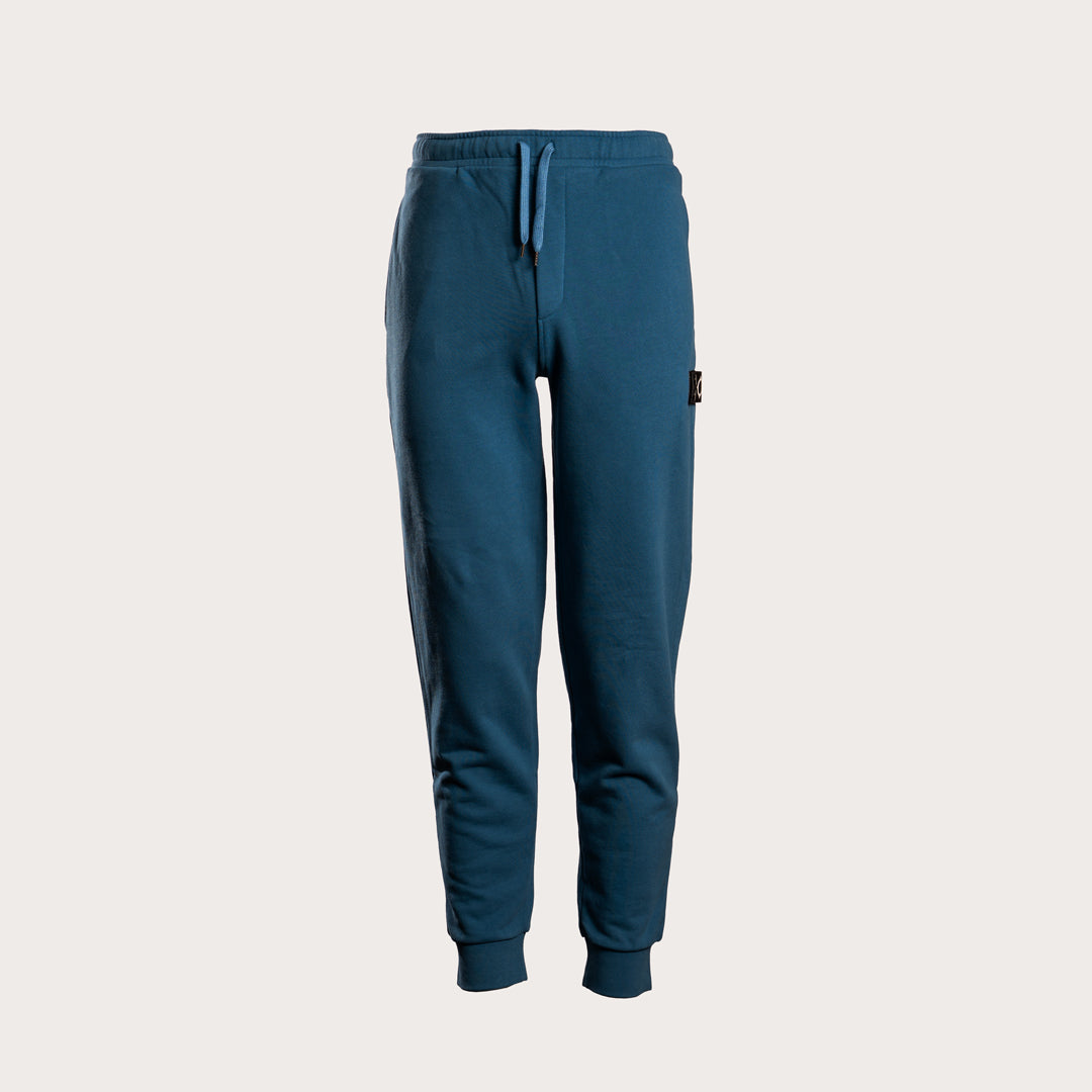 A pair of dark teal blue sweatpants with a drawstring waist and ribbed cuffs, shown against a light beige background. MA.Strum Sweat Pants available at Sakks Menswear in Southampton.