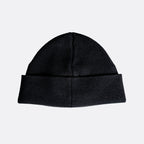 A black ribbed knit beanie hat with a folded cuff, shown against a plain light gray background. MA.Strum Beanie available at Sakks Menswear in Southampton.