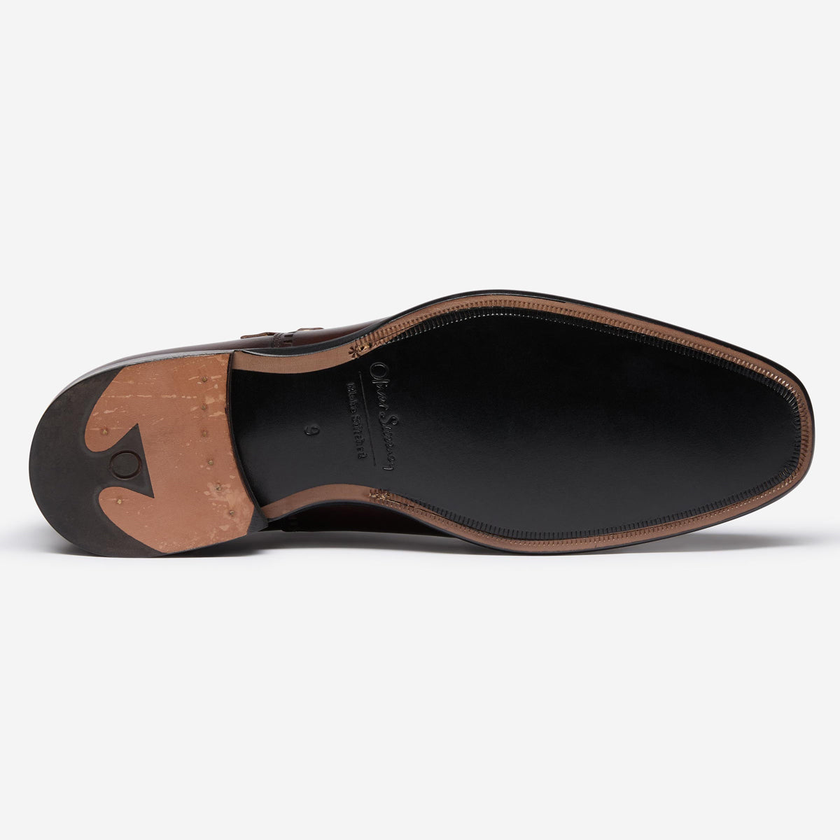 A top-down view of a men's dress shoe showing the black leather outsole, tan rubber heel, and brown stitching along the edge, on a light gray background. Oliver Sweeney Shoes available at Sakks Menswear in Southampton.