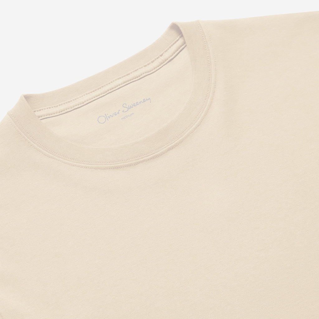 Close-up of a light beige crewneck t-shirt showing the inner collar label with 'Oliver Sempéy' printed in gray. Oliver Sweeney T-Shirt available at Sakks Menswear in Southampton
