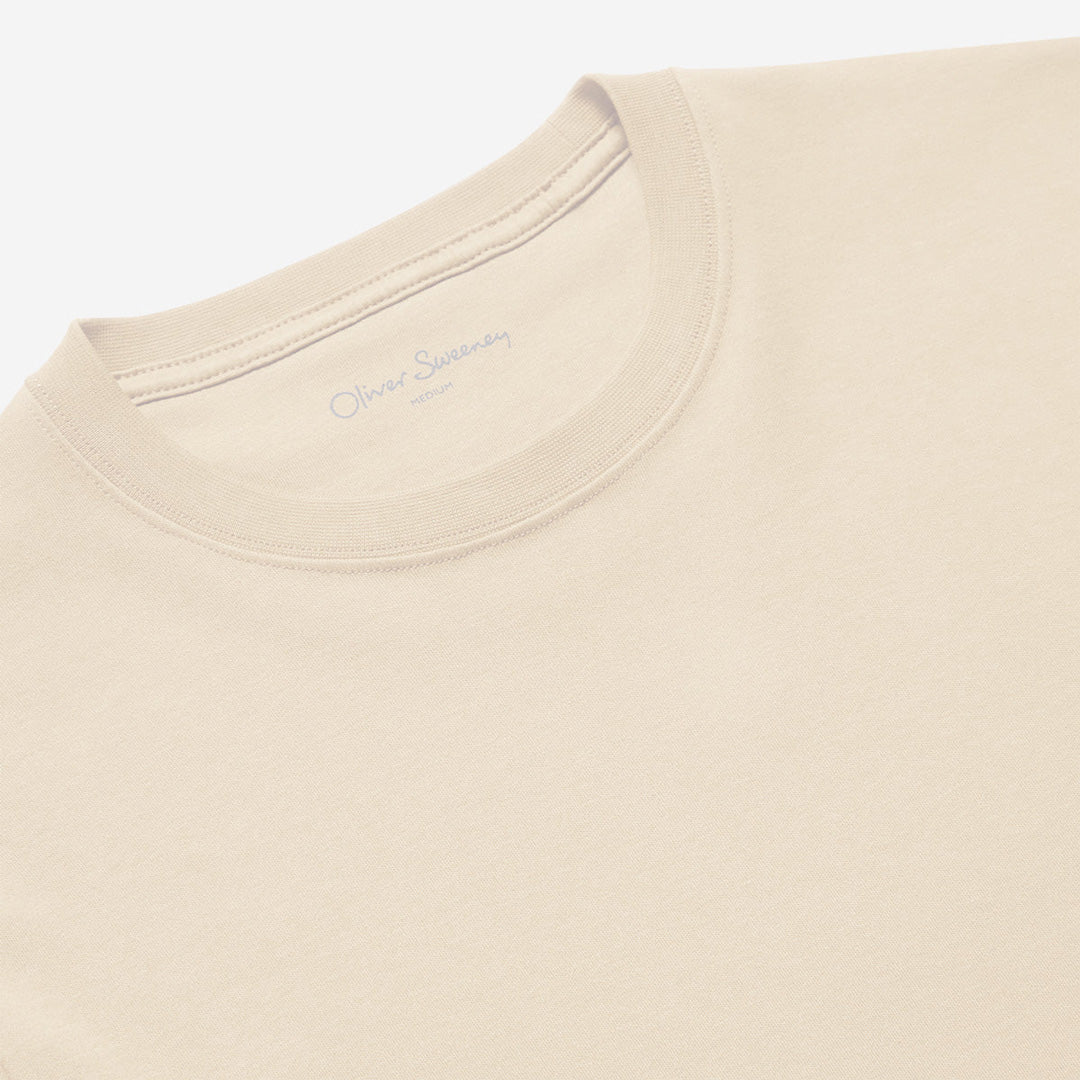 Close-up of a light beige crewneck t-shirt showing the inner collar label with 'Oliver Sempéy' printed in gray. Oliver Sweeney T-Shirt available at Sakks Menswear in Southampton