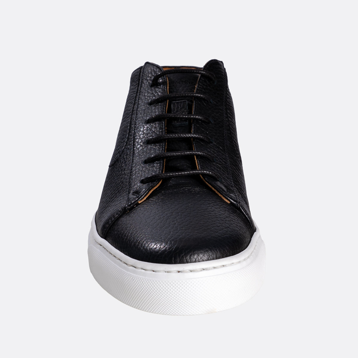 A black leather lace-up sneaker with a textured grain finish, black laces, and a thick white rubber sole, shown from a front-facing perspective on a light gray background. Oliver Sweeney Sneakers available at Sakks Menswear in Southampton.