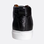 A black pebbled leather high-top sneaker shown from the back, featuring a thick white rubber sole and a small brown pull tab at the collar, set against a plain light gray background. Oliver Sweeney Sneakers available at Sakks Menswear in Southampton.