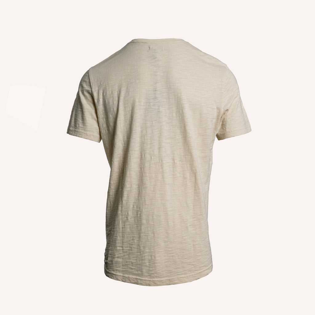 A short-sleeve crewneck t-shirt in a light beige or oatmeal heathered fabric, shown from the back against a solid off-white background. PAIGE T-Shirt available at Sakks Menswear in Southampton.