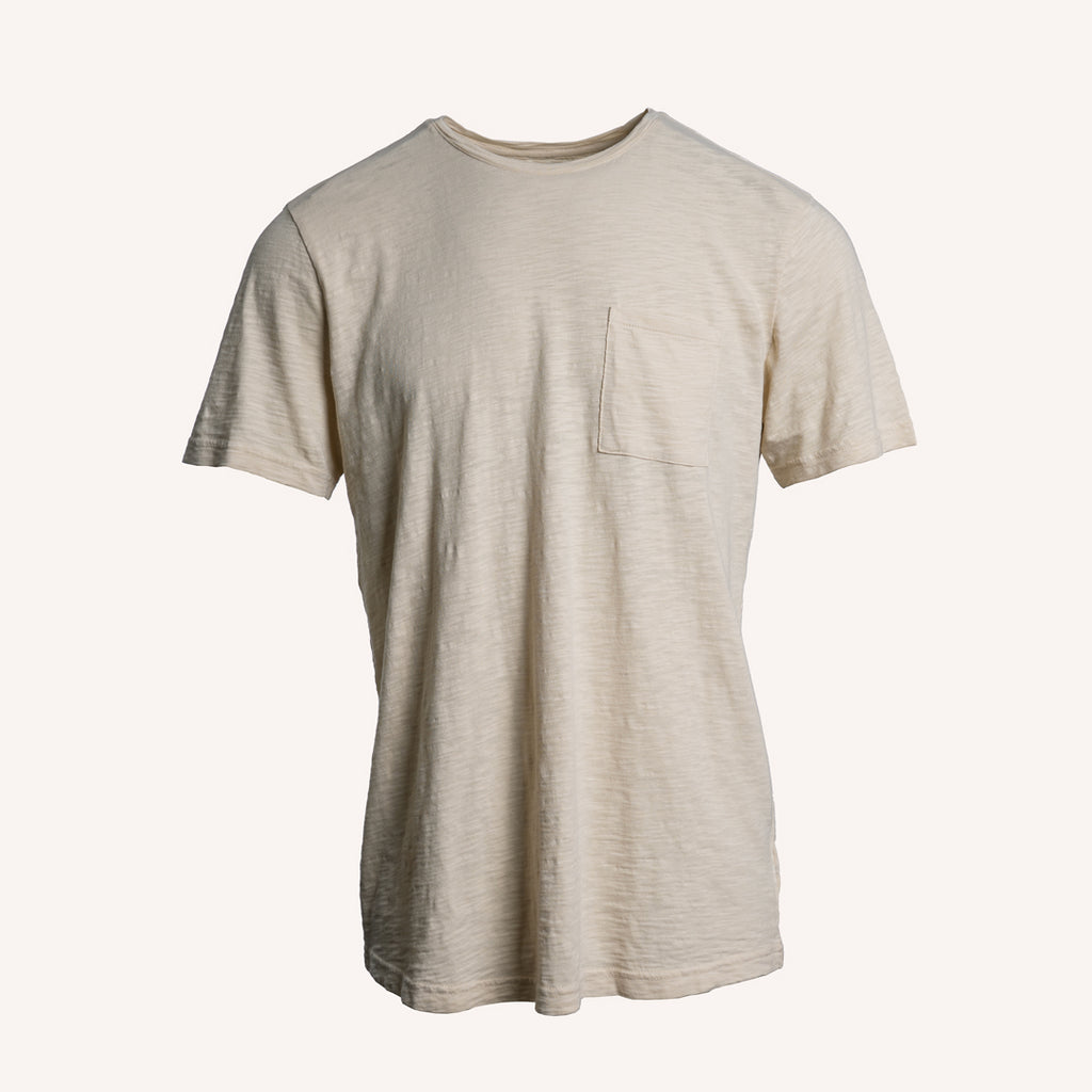 A light beige short-sleeve crewneck t-shirt with a single chest pocket, displayed against a solid off-white background. PAIGE T-Shirt available at Sakks Menswear in Southampton.