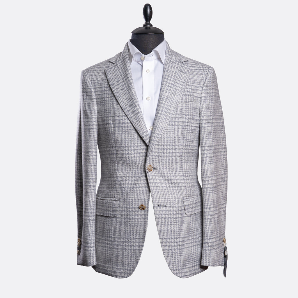 A light gray and white checkered blazer jacket displayed on a black mannequin torso with a white dress shirt underneath, set against a plain light gray background. Sand Copenhagen Blazer available at Sakks Menswear in Southampton.
