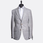 A light gray and white checkered blazer jacket displayed on a black mannequin torso with a white dress shirt underneath, set against a plain light gray background. Sand Copenhagen Blazer available at Sakks Menswear in Southampton.