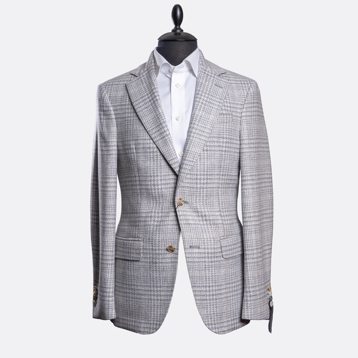 A light gray and white checkered blazer jacket displayed on a black mannequin torso with a white dress shirt underneath, set against a plain light gray background. Sand Copenhagen Blazer available at Sakks Menswear in Southampton.