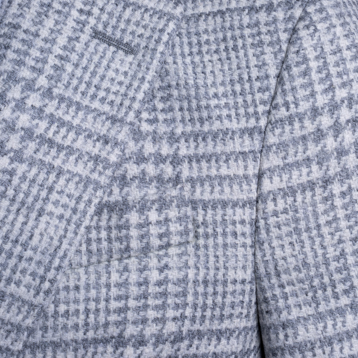 Close-up of a textured fabric with a small-scale blue and white houndstooth pattern. Sand Copenhagen Blazer available at Sakks Menswear in Southampton.
