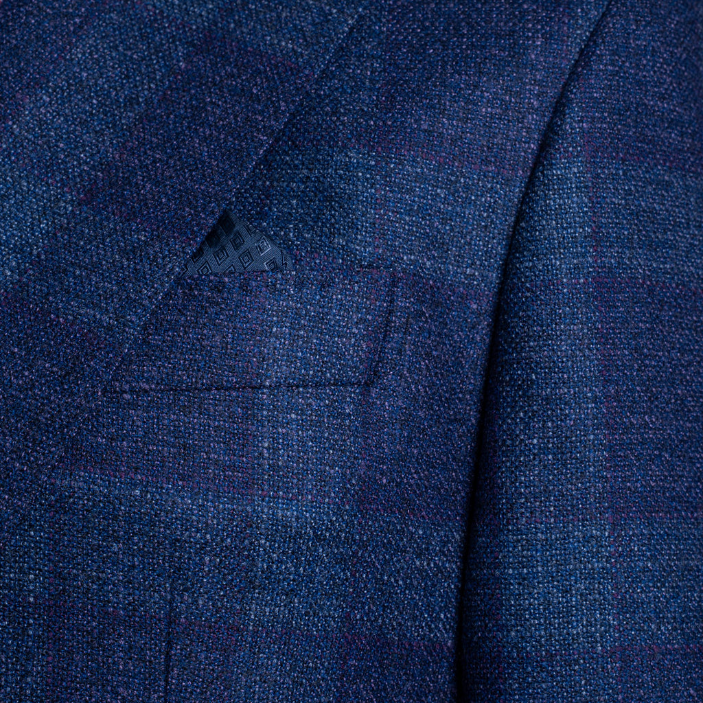 Close-up of a textured navy blue wool fabric jacket with a subtle windowpane plaid pattern and a matching pocket square in the breast pocket. Sand Copenhagen Blazer available at Sakks Menswear in Southampton.