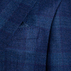 Close-up of a textured navy blue wool fabric jacket with a subtle windowpane plaid pattern and a matching pocket square in the breast pocket. Sand Copenhagen Blazer available at Sakks Menswear in Southampton.