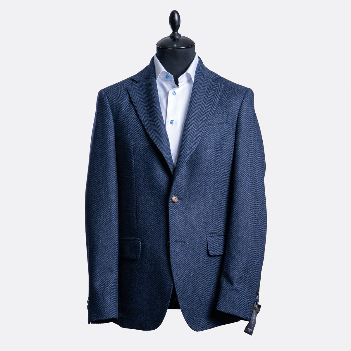 A navy blue textured blazer displayed on a black mannequin torso over a white collared shirt, set against a plain light gray background. Sand Copenhagen Blazer available at Sakks Menswear in Southampton.