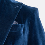 Close-up of a dark navy blue velvet blazer jacket with a pocket and a patterned pocket square, set against a plain white background. Sand Copenhagen Velvet Blazer available at Sakks Menswear in Southampton.