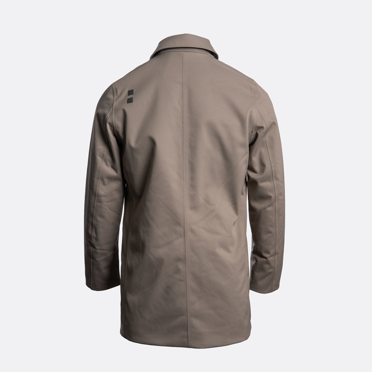 A taupe-brown utility jacket shown from the back, featuring a small black rectangular logo on the upper left shoulder, set against a plain light gray background. UBR Jacket available at Sakks Menswear in Southampton.